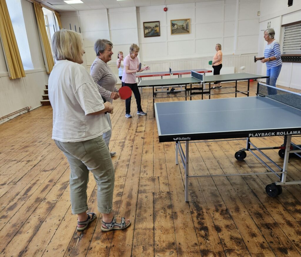 Photograph displaying a group people playing table tennis on 3 tables